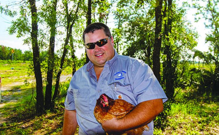 Putnam County Solid Waste Director Jay Tilton with one of the chickens used to help the county monitor viruses caused by mosquitoes.