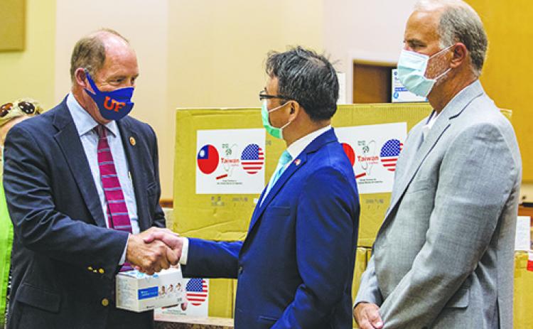 Republican U.S. Rep. Ted Yoho shakes hands with David Chien, general director of the Taipei Economic and Cultural Office in Miami, on Wednesday as he receives 10,000 masks for Putnam County first responders and residents.