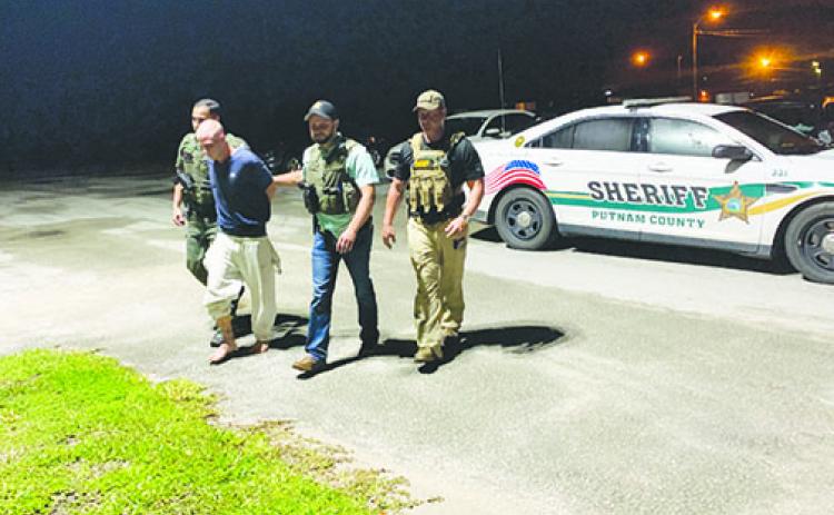 Putnam County Sheriff’s Office investigators walk Mark Wilson Jr. into jail Thursday night after they arrested him for the murders of two young brothers in Melrose a day earlier.