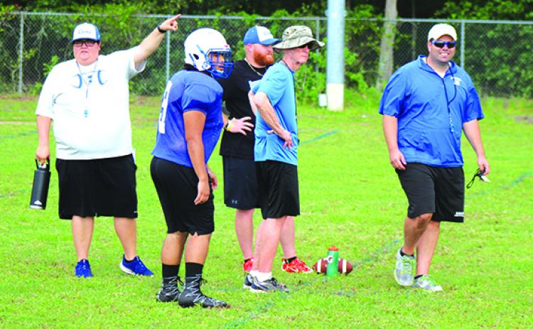 Interlachen High School assistant coach Kim Troiano points to the players where next to go on the IHS practice field, while head coach Matt Yancey, right, smiles. In the middle, from left, are IHS player Giovanni Rosado and assistant coaches Dustin Whitlock and David Criswell. (MARK BLUMENTHAL / Palatka Daily News)