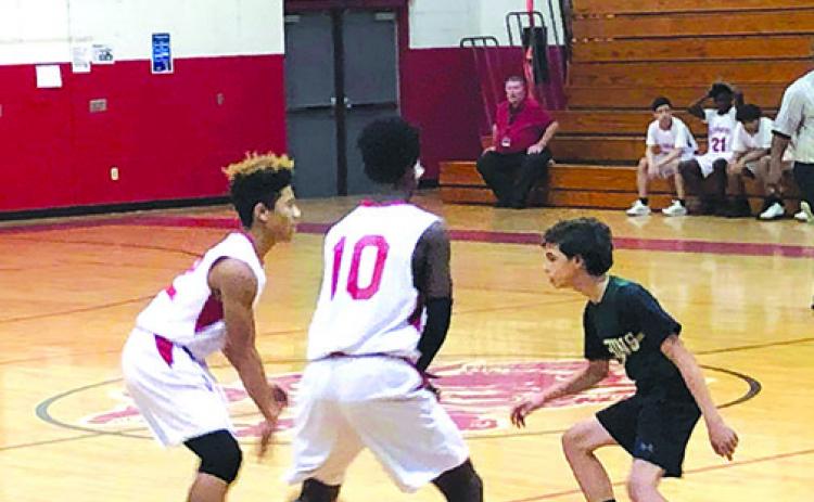 A basketball player from the Putnam Academy of Arts & Sciences, right, guards two C.H. Price Middle School players during a game last season. District officials have postponed middle school sports until spring.