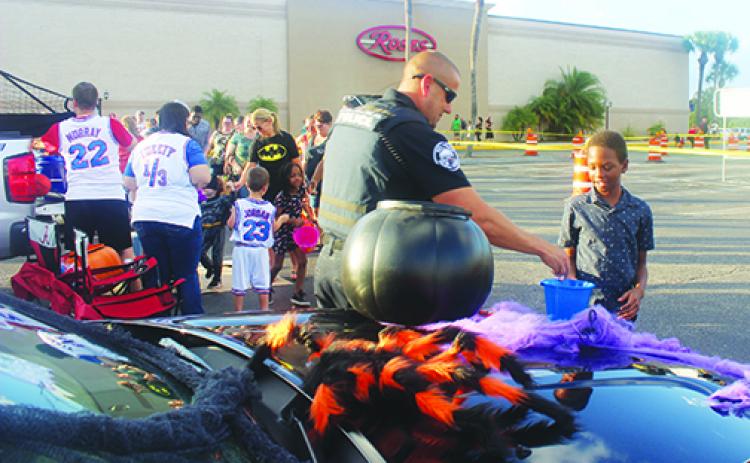 A first responder hands out candy to a line of children at last year’s Trunk or Treat at Palatka Mall.
