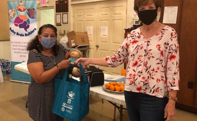 Baby Brain Builders President Angela Mills, right, gives one of the organization’s bags to a local resident recently. The nonprofit organization encourages parents and caregivers to talk to their babies and sound out words.