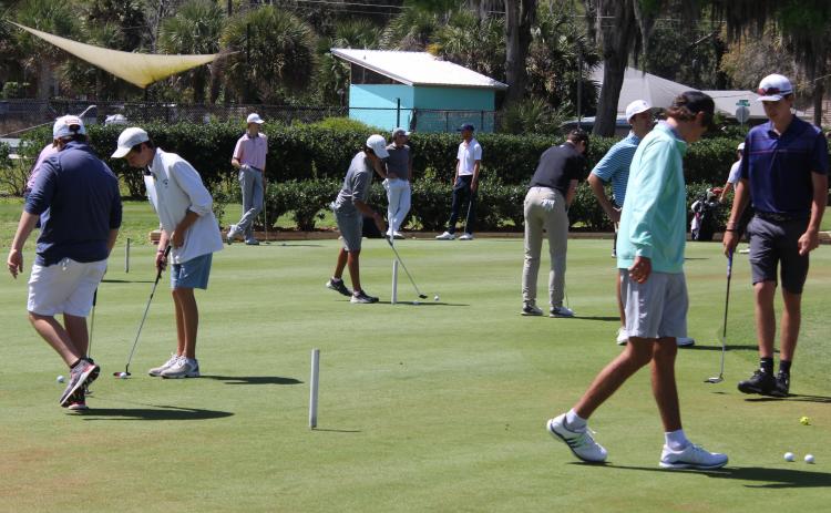 Several golfers practice putting prior to starting their first round. (MARK BLUMENTHAL / Palatka Daily News)