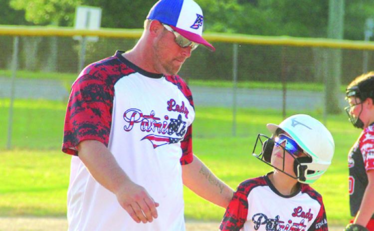 Brandon Zurn, left, talks to one of his players with the Palatka Lady Patriots, a 10-and-under softball team during a game this week. (ANTHONY RICHARDS / Palatka Daily News)