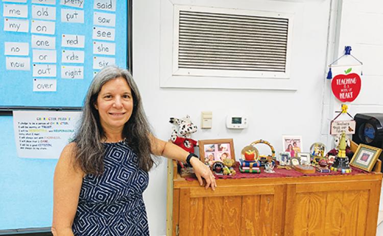 Middleton-Burney Elementary School first grade teacher Lynn Skelton, who has taught at the school for 42 years, stands in her classroom in front of pictures and other mementos she’s collected during her decades-long teaching career. 