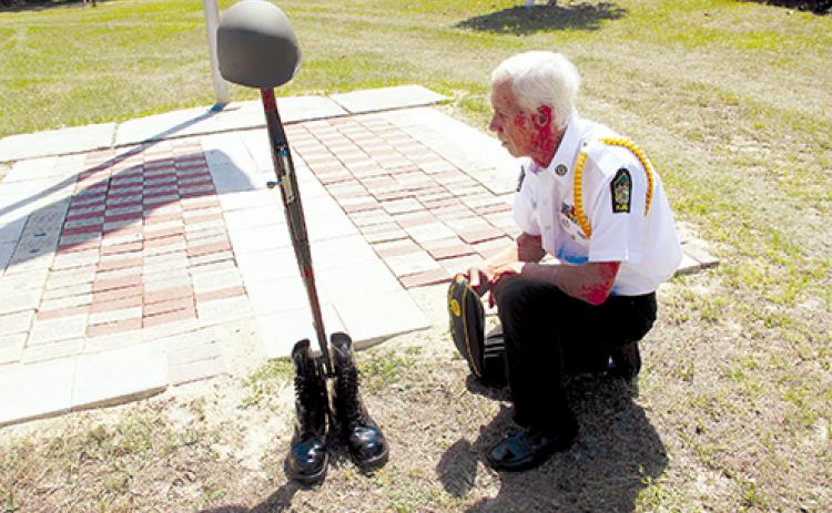 Don Hartsfield, post commander of American Legion Post 293 in Interlachen, kneels at a tribute to the unknown soldier representing all fallen soldiers who never came home from combat during wartime.