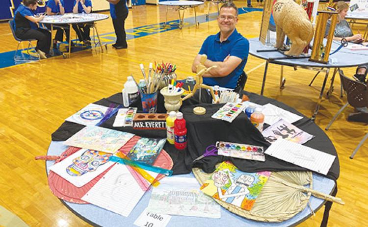 Palatka High School art teacher Michael Everett sits at a table displaying samples of work prospective students could be creating in his class. Everett was one of the teachers who participated in the school’s orientation for students who will begin attending the school during the next academic year.