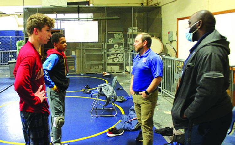 Josh White (second from right) chats with state tournament wrestlers Brandon Lewis (left) and Mikade Harvey, while assistant coach Elisha Campbell listens at right during a practice in March. (MARK BLUMENTHAL / Palatka Daily News)