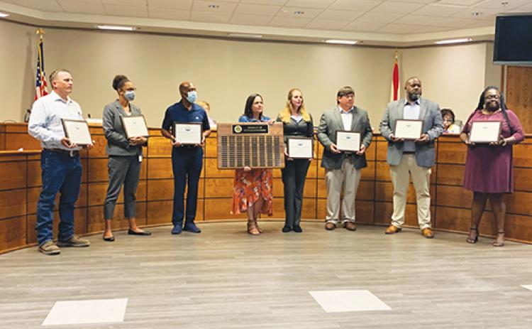 Scott Brauman, Sharice Williams, Wade Dallas, Heather Hoffman, Matt Buckles, Aaron Hall and Trinisha Austin hold their Product of Putnam awards at Tuesday’s Putnam County School District board meeting as Community Relations Director Ashley McCool, center, holds the plaque on which their names are etched.