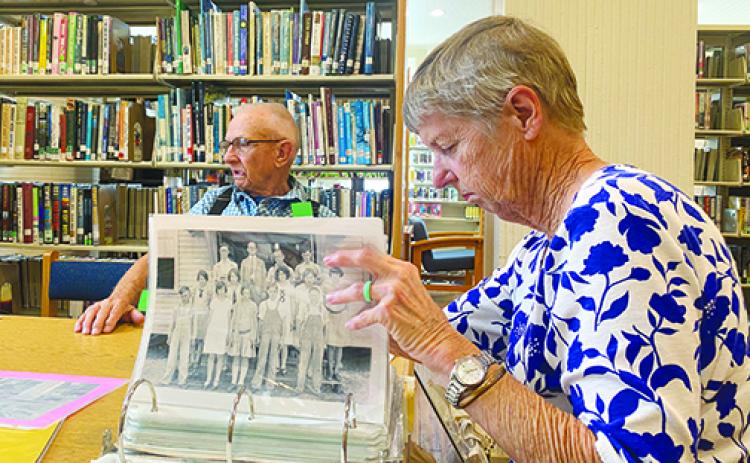 Former Bostwick Library Branch Manager Claudia Wilkinson looks over photos of the building as her husband, Charlie Wilkinson, recalls memories from when he went to school in the same building during the 1940s.