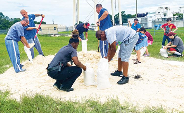 Putnam County officials, residents and members of the county’s inmate work crew fill bags of sand Tuesday at the East Palatka Community Park.