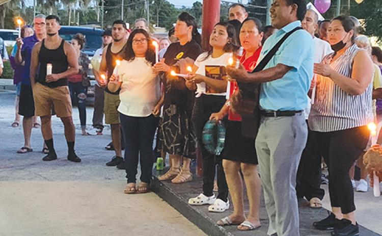 A small choir sings during a vigil service for Mark Anthony Arbelo Jr., held at his father’s business on Friday night in Crescent City.