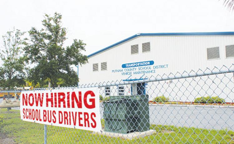 A sign advertising the need for school bus drivers hangs on the fence surrounding the bus depot in Palatka.