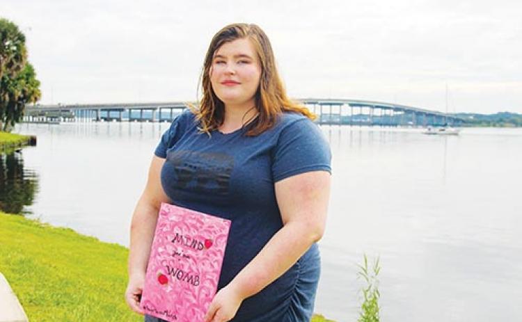 Welaka resident Jani Baldwin stands in front of the Palatka riverfront Tuesday holding a sign that says, “Mind your own womb.”