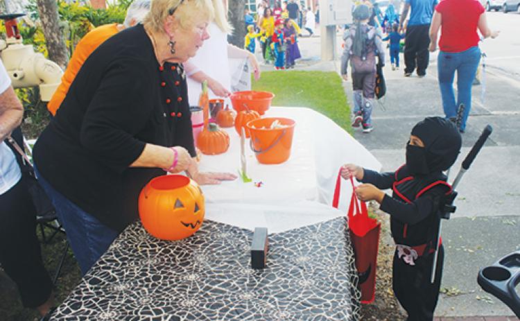 A diminutive ninja, one of more than 1,000 children who attended the 2019 Boo on the Avenue, receives candy as he strolls along St. Johns Avenue in Palatka.