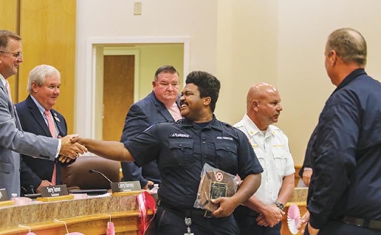 Joshua Florence, a volunteer firefighter with the Melrose Fire Department, shakes hands with Putnam County Board of Commissioners Chairman Larry Harvey after receiving a plaque from the county for service to the community and for being recognized as Florida’s Volunteer Firefighter of the Year.