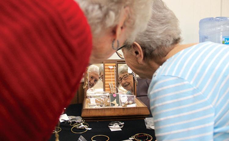 St. James United Methodist Church members Carolyn Flanders’, left, and Ruth Vickers’ images can be seen in the jewelry box mirror set up with items for sale at the church’s annual bazaar.