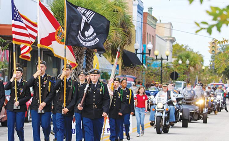Palatka Junior-Senior High School JROTC cadets raise the state, American and Prisoner of War flags while they march down St. Johns Avenue in the Veterans Day parade on Thursday.