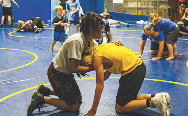 Tenth-grader Damaris Carr, left, prepares for a takedown wrestling move Thursday with eighth-grader Dayron Wright.