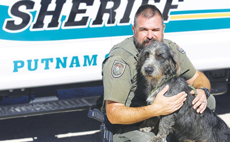 Putnam County Sheriff’s Office Master Sgt. Randy Hayes pets an adoptable dog last month. The agency collected 1,306 pounds of pet food and 122 blankets for Animal Control in November.