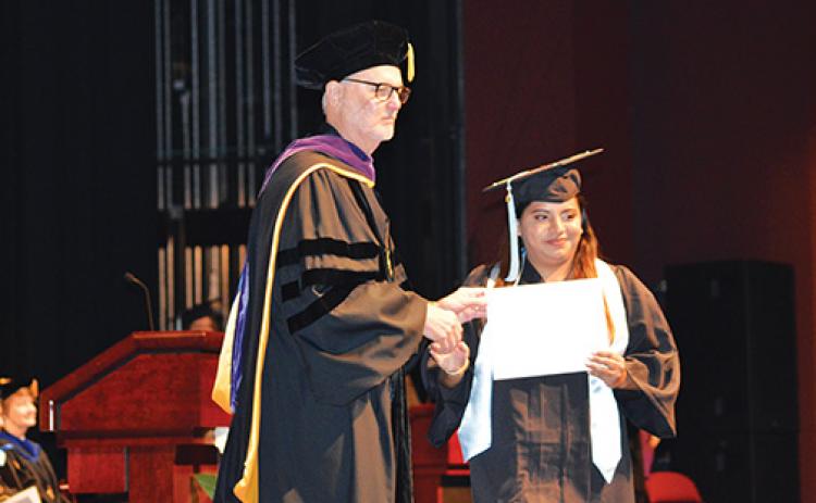 Graduate Patricia Martinez accepts her diploma from SJR State President Joe Pickens during the commencement ceremony.