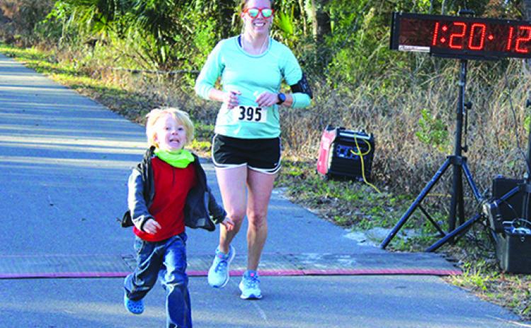 With son Kai running alongside her at the end, Talisa Fletcher crosses the finish line to win the Life Half Marathon women’s title last year at the Coventry Oaks Farm. (MARK BLUMENTHAL / Palatka Daily News)