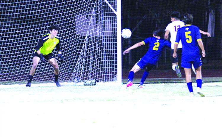 Crescent City’s Jesus Cruz (12) tries a headball past Trinity Prep defender Matthew Ahl (2) as goalkeeper Shane Wright waits for the ball during the first half of Wednesday’s District 5-3A final. Wright would make one of his five saves on the night here. (MARK BLUMENTHAL / Palatka Daily News)
