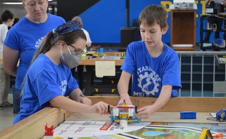 Melrose Elementary School sixth-grader Irik Weeks, right, and fifth-grader Haleyigh Stegall test an autonomous LEGO robot their “Starhorse” robotics team created for the FIRST LEGO League Qualifying Tournament at Palatka High School on Saturday as teacher and co-coach Bonnie Tillson looks on.
