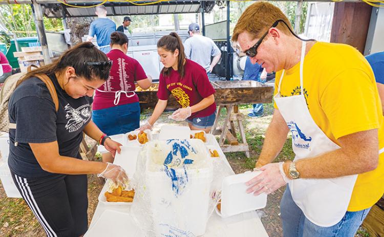 Volunteers at the 2019 Crescent City Catfish Festival pack plates of fried fish, hushpuppies and coleslaw to sell to festival-goers.