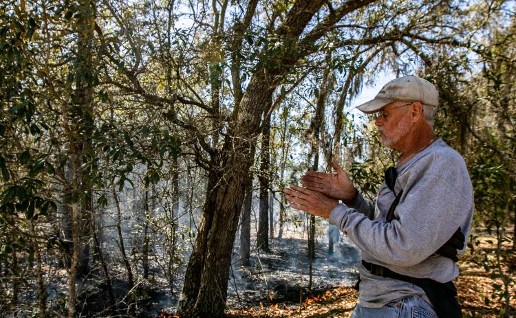 Photo by Sarah Cavacini/Palatka Daily News. Ben Williams describes the prescribed burn process Sunday as the Wetland Preserve grounds burn behind him.