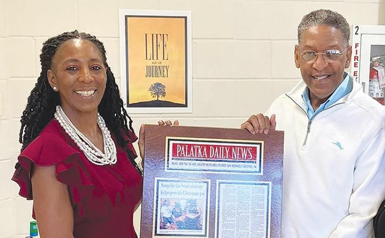 Catherine Mercer, left, is pictured with Aaron Robinson, Palatka Housing Authority’s director of social services, holding a plaque of a Palatka Daily News story that was written about Mildred Brockington’s ministry in the community to help those in need. 