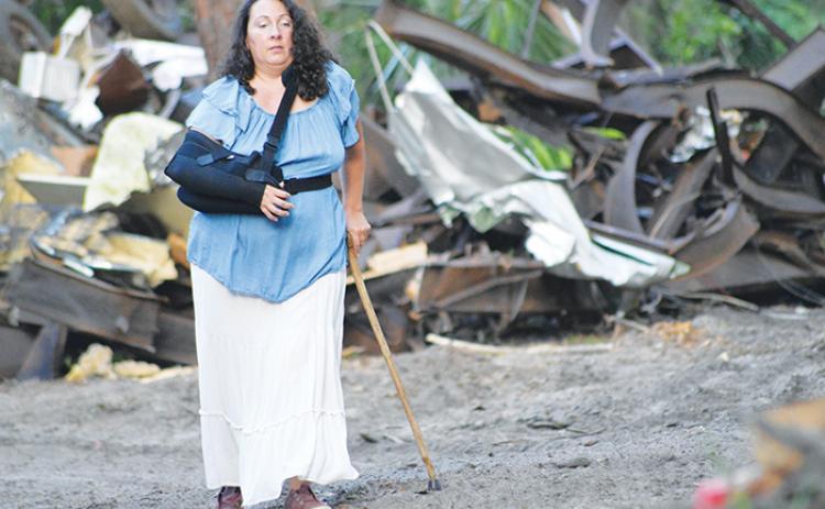 Shanna Cruz walks in front of a pile of debris at the St. Johns Campground in East Palatka on Friday evening.