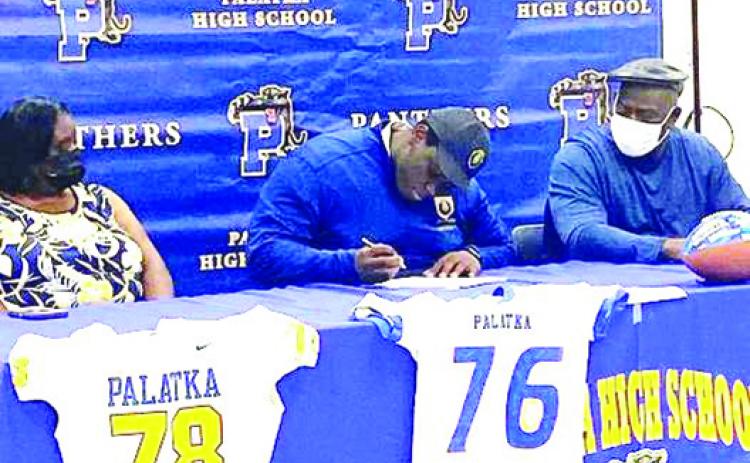 Palatka offensive lineman Daunte Wilkerson signs his letter of intent to play at Warner University in February. Watching are his mother LaTrecia, left, and father, Alvoid Maples. (Photo courtesy of Palatka Football Facebook Page)