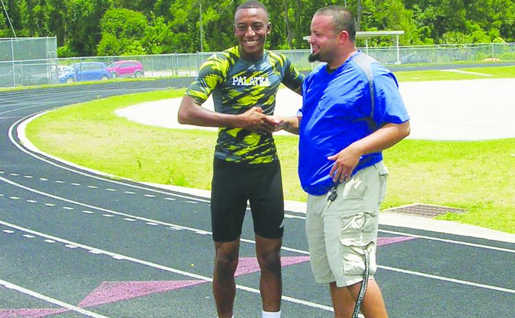 Steven Gonzalez (right) congratulates Ka’Ven Berry on being named Daily News Boys Track Athlete of the Year in 2013, the same year Gonzalez was named Daily News Coach of the Spring for the first time. Berry is now Gonzalez's assistant coach at Jacksonville Mandarin High School. (MARK BLUMENTHAL / Palatka Daily News)