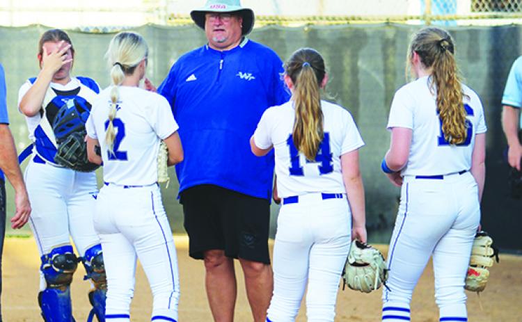 Peniel Baptist Academy softball coach Jeff Hutchins talks in between innings with players (from left) Summer Langston, Brook Williams, Allie Peacock and Lexi Peacock during the team’s win at home against St. Joseph’s Academy last month. (MARK BLUMENTHAL / Palatka Daily News)