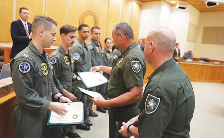 Sheriff's office officials award certificates to the Navy crews who rescued a pilot who made an emergency landing in a pond.