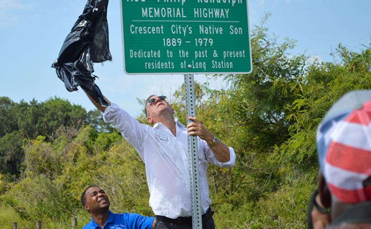 Putnam County Commissioner Larry Harvey unveils the new Asa Philip Randolph Memorial Highway Sign in Crescent City while Pastor Ty Fields Sr. makes sure he doesn’t fall.