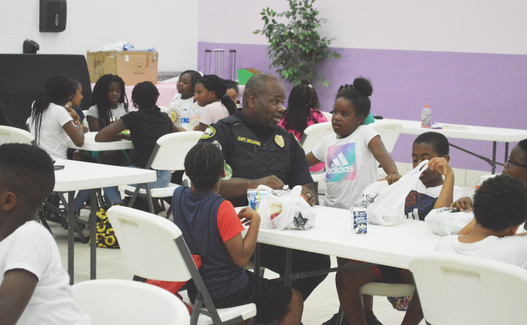 Capt. Tobby Williams has lunch with campers at Camp Higher Ground Monday morning. The camp is one of the Palatka Police Department's biggest community outreach programs.