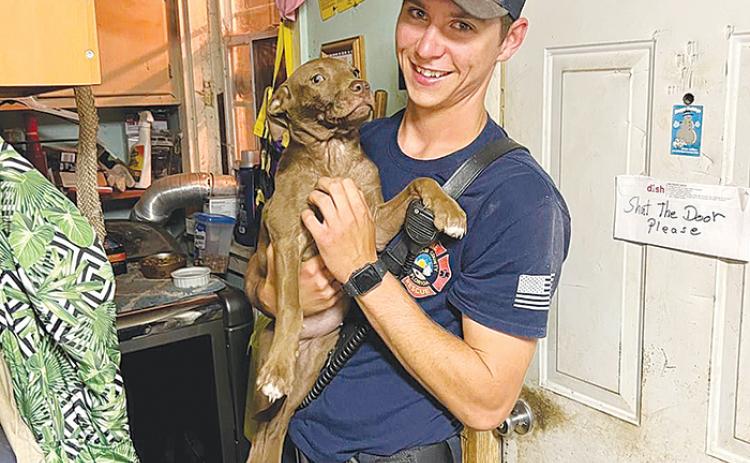 Putnam County firefighter and EMT Jacob Woods holds a Georgetown family’s puppy after helping rescue the little guy from a recliner chair where he was stuck Tuesday morning.