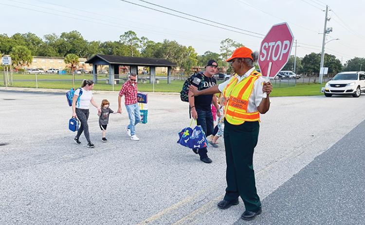 A Palatka crossing guard helps parents and students safely cross the road on the first day of school Wednesday.