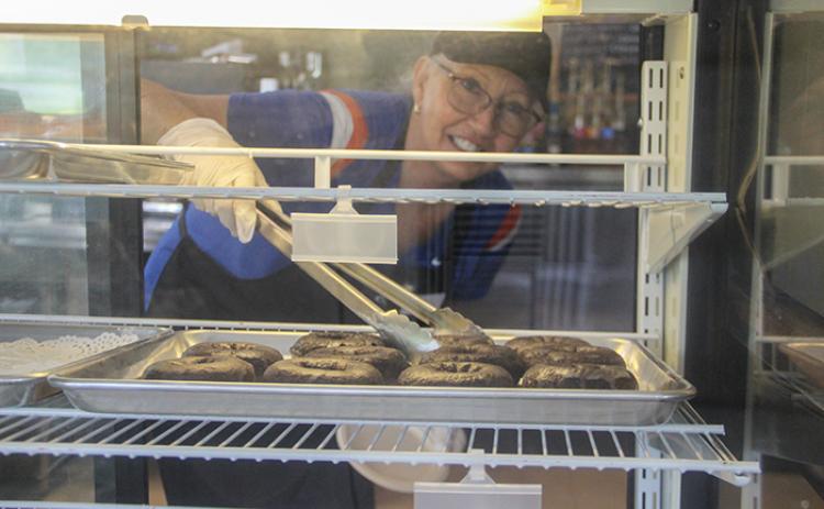 Kathi Hanks grabs a chocolate glazed donut Thursday at Beanz N’ Cream Cafe in San Mateo.
