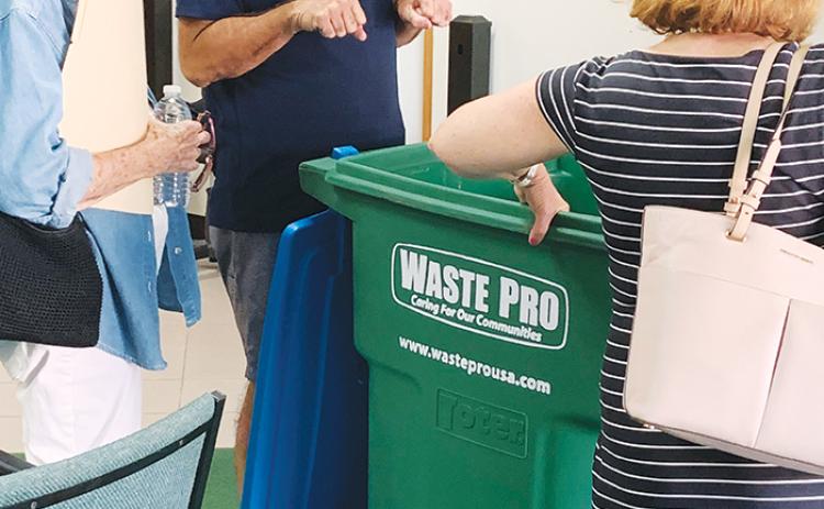 From left, Pat Mangan, Scott King and Crescent City Commissioner Lisa Devitto examine a 96-gallon WastePro trash bin at Crescent City’s City Hall.
