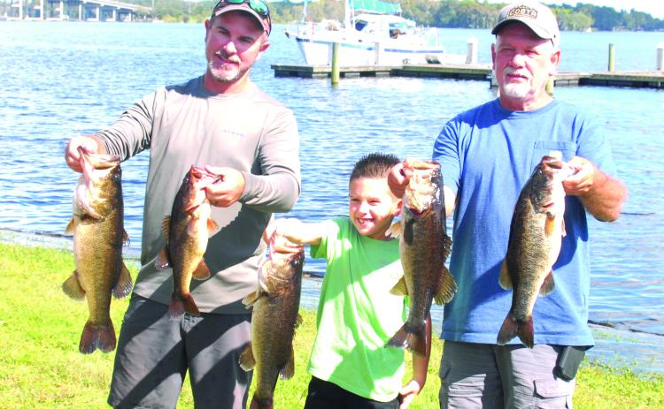 Justin Atkinson, Justin Atkinson, Jr. and Brett Bollinger hold up their winning fish at the Invitational Bass Tournament last weekend. (GREG WALKER / Daily News correspondent)