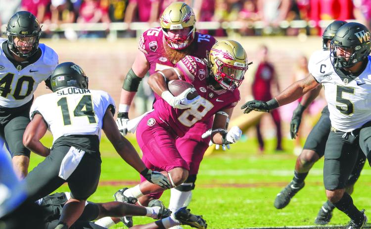 Florida State’s Treshaun Ward darts through a hole as Wake Forest’s Evan Slocum (left) and Ryan Smenda Jr. pursue Saturday in Tallahassee. (GREG OYSTER / Special to the Daily News)