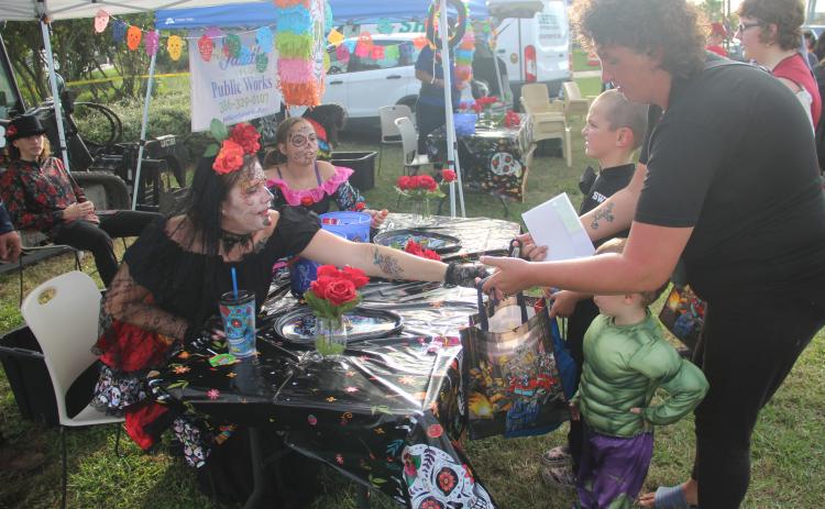 Adah Bridges hands out candy at her "Day of the Dead" themed booth at the Palatka Riverfront on Halloween.