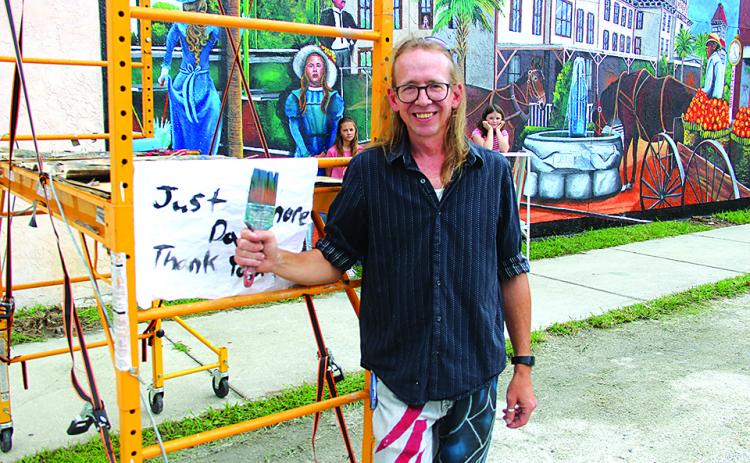 Luke Taft takes a break from his last day of painting while standing in front of the scaffold he used for the large project the Putnam House mural. (TRISHA MURPHY / Palatka Daily News)