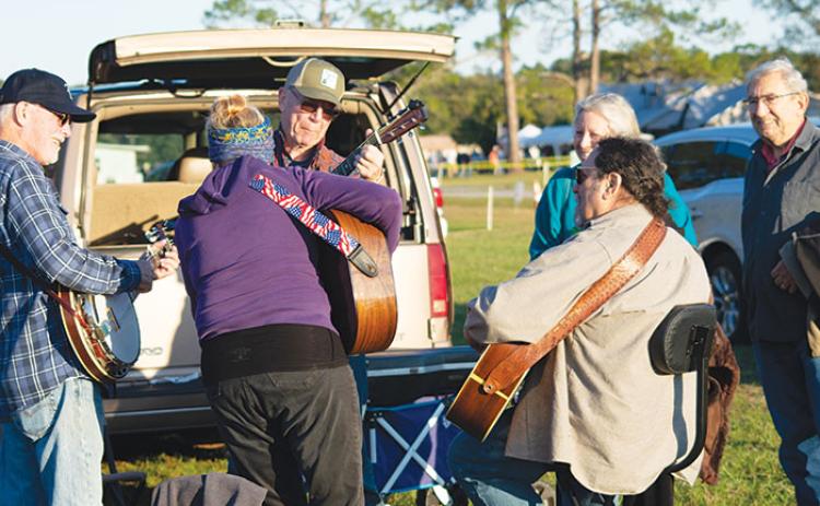 From right, Mike Luddeni of Ormond Beach and his friend Lisa Cummins of The Villages stop to listen to a spur-of-the-moment bluegrass jam by fellow enthusiasts Mike Elas, seated, and Bob Tice of St. Augustine, guitarist Lynn Healy of Fleming Island and banjo player Brian Lappin of Flagler Beach.