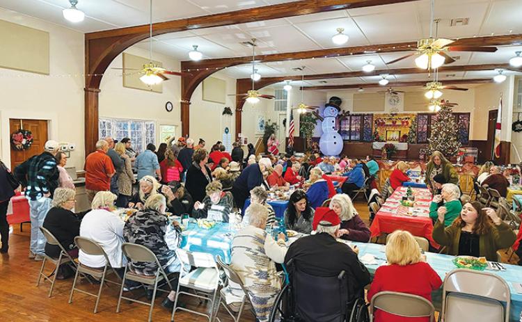 People line up for food and mingle Saturday at the Pomona Park Community Center during the town’s first Christmas Eve dinner put on by the Pomona Park Beautification Committee.