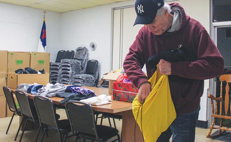 First Presbyterian Church of Palatka Pastor Cliff Lyda looks through a bag of clothing Monday night that was given to people seeking shelter from the cold at the church’s fellowship hall.